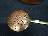 a metal strainer sitting on a table next to a pot