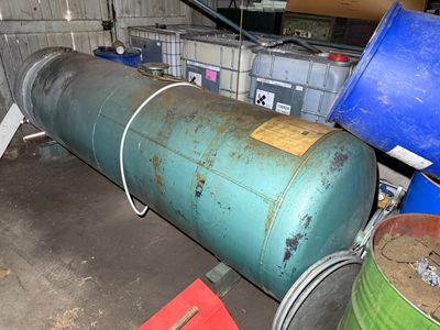 a large green tank sitting next to a blue barrel