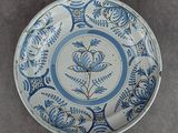une vieille assiette bleue et blanche ornée d'un motif floral