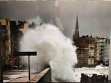 une photo montrant une grande vague déferlant sur un mur