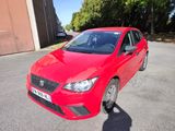 La voiture rouge est garée sur le parking, à côté d'un immeuble.