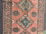 un vieux tapis orné d'un motif en losanges, posé à même le sol