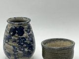deux vases posés l'un à côté de l'autre sur une surface blanche