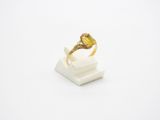 un gros plan d'une bague avec une pierre jaune sur un fond blanc