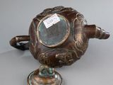 a bronze teapot with a lid on a table