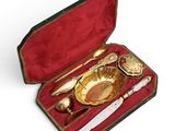 un plateau en or et des couverts en argent dans un coffret rouge