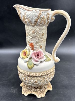a white vase with a pink rose on it on a table