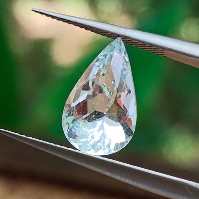 un gros diamant transparent tenu par une paire de pinces