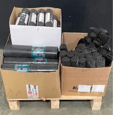 de nombreux rouleaux de tissu noir dans des cartons posés sur une palette