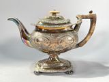 silver plated teapot with a bird on top of it