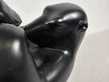 a black sculpture of a woman laying down on a white surface