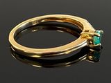 an image of a close up of a gold ring with a green stone