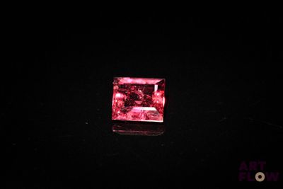 a close up of a pink diamond on a black surface