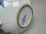 a blue and white vase on a table with a tag on it