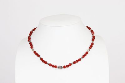 un gros plan d'un collier sur un mannequin, orné de perles rouges