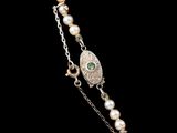 a close up of a necklace with pearls on a black background