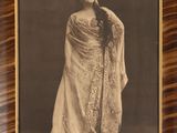 an old photo of a woman in a dress is hanging on a wall