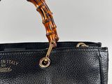 a close up of a black handbag with a bamboo handle