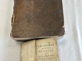 an old book sitting on top of a white sheet next to a book