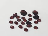 a close up of a bunch of red garnets on a white surface