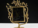 a gold mirror on a stand with a leaf design on it