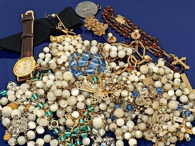 un tas de bijoux posés sur une surface bleue, avec une montre