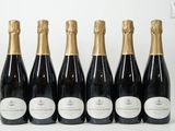 six bouteilles de champagne alignées sur une surface blanche