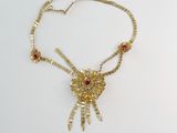 collier en or orné de pierres rouges sur fond blanc