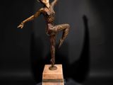 bronze statue of a woman in a pose on a wooden base