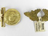 two pieces of gold colored metal with a medal and a pin