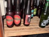 bottles of beer are lined up on a wooden shelf in a room