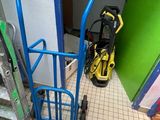 un diable bleu avec une poignée rouge à côté d'une porte verte