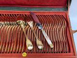 silverware in a red case with gold handles and spoons in it