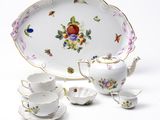 a white plate with flowers on it and a tea pot and saucer