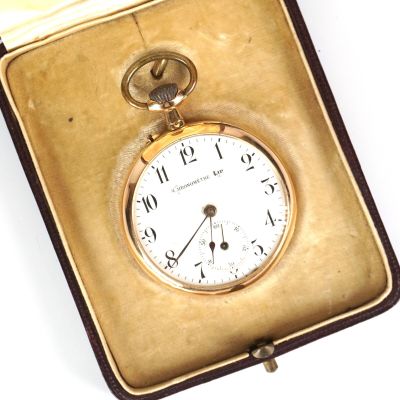 une montre de poche en or dans un écrin posé sur une surface blanche