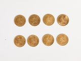several gold coins are arranged in a row on a white surface