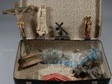 une valise remplie de statuettes religieuses et d'un crucifix
