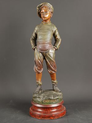 a bronze statue of a boy standing on top of a wooden base