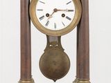 une petite horloge en bois posée sur une table, avec un mur blanc en arrière-plan