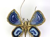 broche en forme de papillon bleu et or sur fond blanc