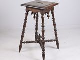 an old wooden table with a small square top on a white floor