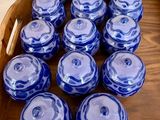 de nombreux bocaux en verre bleus et blancs dans une caisse en bois