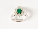 a close up of a ring with a green stone surrounded by white diamonds