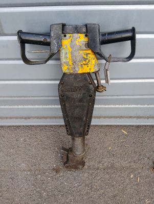 a close up of a drill on the ground next to a garage door