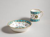 two cups and a saucer sitting on a white surface