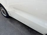 a white car that has been dented and is parked on the street