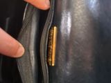 a person holding a black purse with a gold button on it