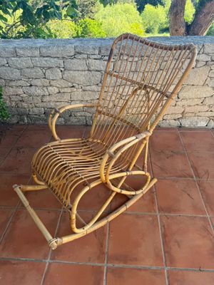 a wicker rocking chair sitting on a brick patio