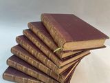 six old books stacked on top of each other on a white surface