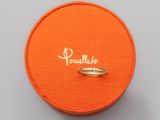 une boîte orange contenant un anneau sur lequel est inscrit le mot « paulloo »